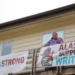 Award-winning Juneau writer Vera Starbard stands on her balcony on Douglas Island that displays banners across Gastineau Channel in support of the Writers Guild of America union strike currently going on across Hollywood and the country. (Clarise Larson / Juneau Empire)