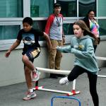 Sayéik: Gastineau Community School physical education teacher Dirk Miller watchs students William Olmstead and Allie Simonson clear hurdles during Field Day at the school on Thursday. Miller is retiring after 24 years at the school. (Klas Stolpe / Juneau Empire)