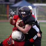 Members of Team World take down Team Juneaus Stefan Jones, JDHS class of 2013, during Friday nights alumni game. (Ben Hohenstatt / Juneau Empire)