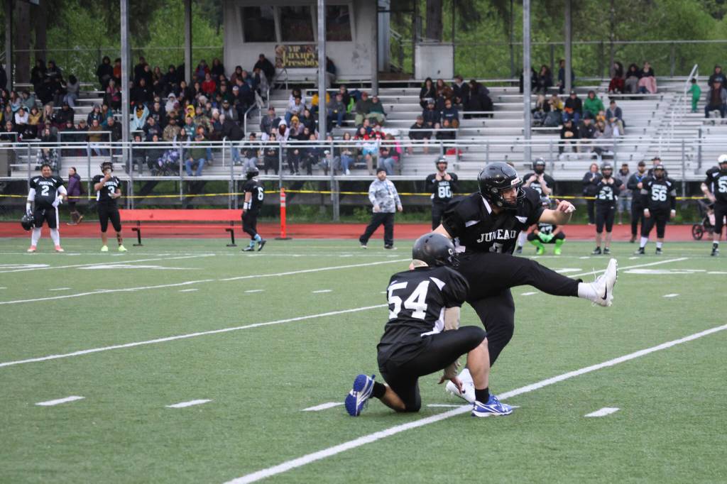 Team Juneaus Steve Lewis, JDHS Class of 1998, holds the ball for teammate Mahina Toutaiolepo, TMHS class of 2017, whose foot put the first 3 points of the 2023 Alumni Game Friday night at Adair-Kennedy Memorial Field. (Ben Hohenstatt / Juneau Empire)
