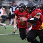 Team Worlds Lance Fenumiai (2), JDHS class of 2018, rushes down the field while teammate Tristan Thomas (50), class of 2015, looks to throw a block during the 2023 Alumni Game played Friday at Adair-Kennedy Field. (Ben Hohenstatt / Juneau Empire)