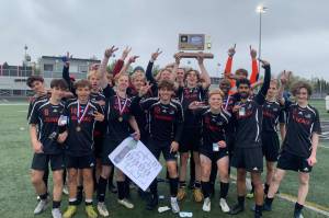 The Juneau-Douglas High School: Yadaa.at Kalé Crimson Bears boys soccer team pose with their championship trophy after defeating Soldotna 4-0 for the ASAA DII Boys Soccer State Championship, Saturday, at West Anchorage High School (Courtesy Photo / JDHS Soccer)
