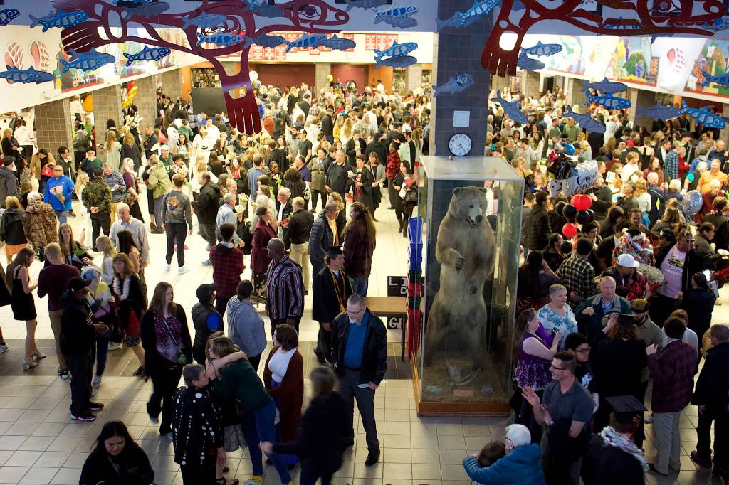 Mac the Bear watches over graduating seniors and their families in commons area of Juneau-Douglas High School: Yadaa.at Kalé on Sunday. Juneau School District Superintendent Bridget Weiss said when she graduated from JDHS back in 1980 the commons area was still undeveloped and Mac the Bear  who was on wheels instead of in a glass cage  often ended up making trips into unexpected rough terrain. (Mark Sabbatini / Juneau Empire)