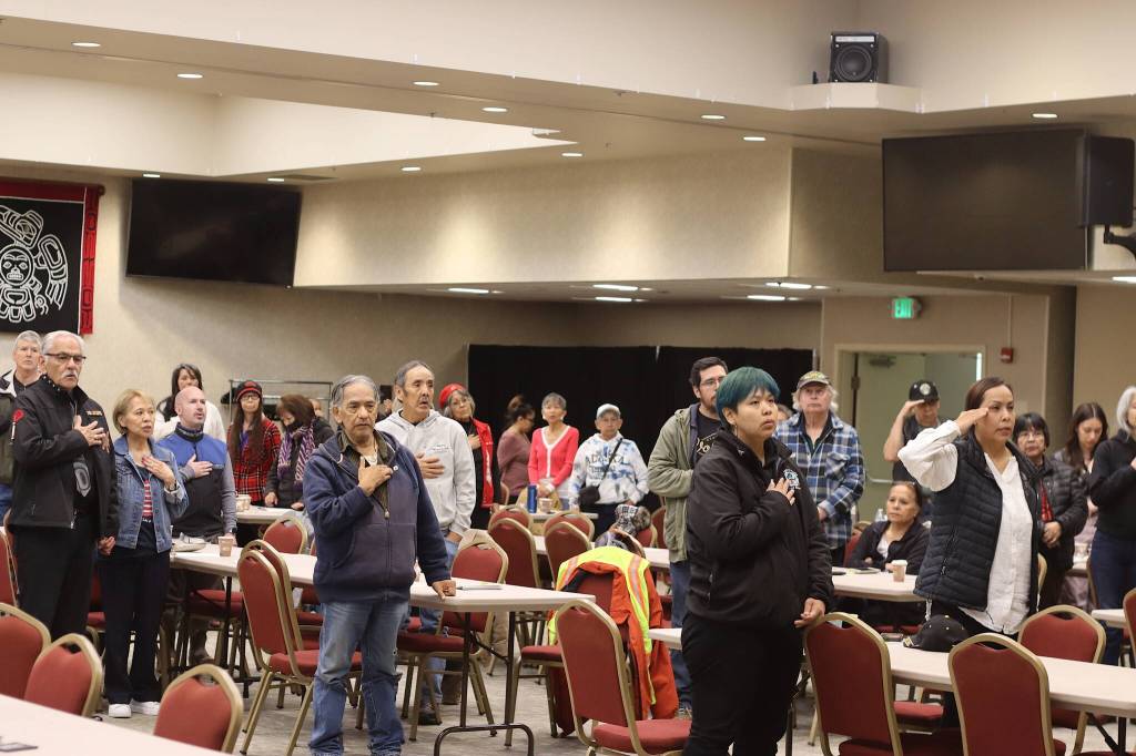 Attendees at the Southeast Alaska Native Veterans Memorial Day observance stand for the singing of the Star Spangled Banner by Navy veteran Bob Ridley on Monday at Elizabeth Peratrovich Hall. (Mark Sabbatini / Juneau Empire)