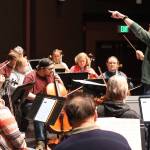 Christopher Koch, music director of the Juneau Symphony, conducts a rehearsal of the theme from the 1989 Batman movie in the auditorium at Juneau-Douglas High School: Yadaa.at Kalé in preparation for two concerts this weekend at the school featuring familiar soundtrack compositions from films with showdown plot lines. (Mark Sabbatini / Juneau Empire)