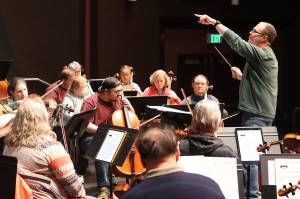Christopher Koch, music director of the Juneau Symphony, conducts a rehearsal of the theme from the 1989 Batman movie in the auditorium at Juneau-Douglas High School: Yadaa.at Kalé in preparation for two concerts this weekend at the school featuring familiar soundtrack compositions from films with showdown plot lines. (Mark Sabbatini / Juneau Empire)