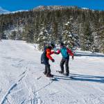 Sitka participant Reece Howard (left), on one of his first runs holds hands for support with chaperone Lee House (right). (Photo by Lione Clare / Sitka Conservation Society)