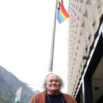 Writer Jane Hale smiles for a photo as the wind blows a newly raised LGBTQ+ flag at the Hurff A. Saunders Federal Building downtown. (Clarise Larson / Juneau Empire)