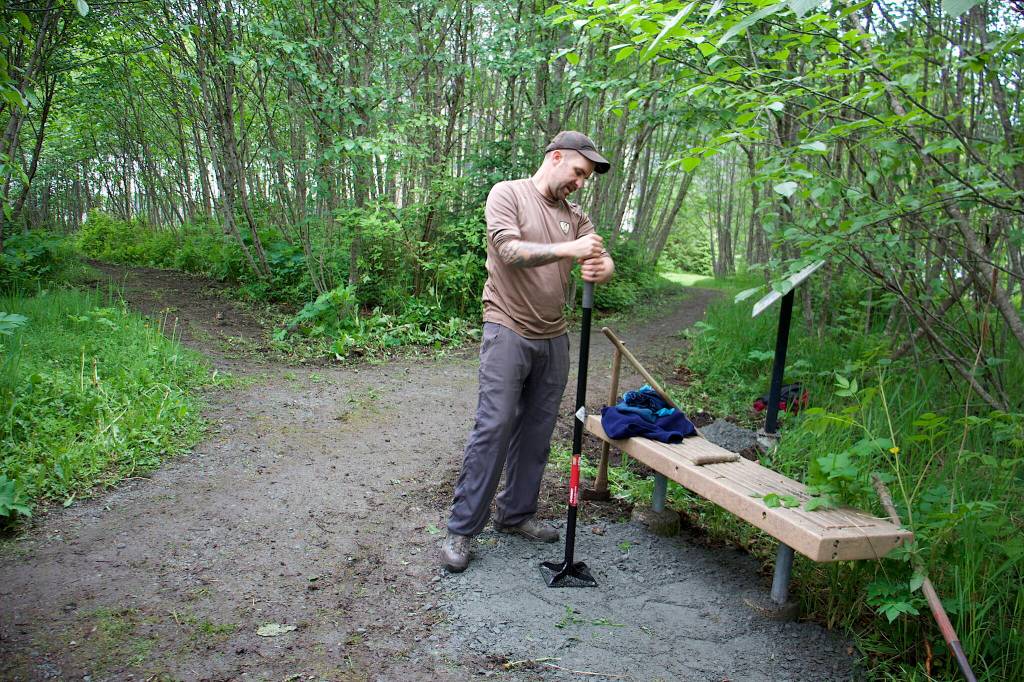 Ryan OShaughnessy, executive director of Trail Mix, packs gravel down by hand at a juncture of the Kingfisher Pond Loop Trail on Saturday. (Mark Sabatini / Juneau Empire)