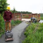 Chris Meade, a board member of Trail Mix and Juneau resident since 1991, uses a vibrating plate compactor to compress gravel leading to a viewing platform along the Kingfisher Pond Loop Trail on Saturday. (Mark Sabatini / Juneau Empire)