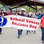 Bob King, center, helps carry a National Cancer Survivors Day banner at the beginning of a local Celebration of Life Walk from Marine Park to Bill Overstreet Park on Sunday. King, afflicted with brain cancer for the past five years, said this is the first year he felt able to participate in the walk as a cancer survivor because his doctors say they can no longer detect the tumor that was in his brain. (Mark Sabbatini / Juneau Empire)