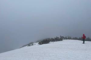 The authors wife hikes down the ridge of a still snow-covered mountain. (Jeff Lund / For the Juneau Empire)