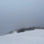 The authors wife hikes down the ridge of a still snow-covered mountain. (Jeff Lund / For the Juneau Empire)