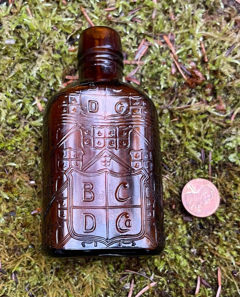 A small artifact bottle Denton discovered while excavating beneath the Senate Building in 1984. Prophetically, it has the same letters embossed in the glass as Dentons business name, BCD Co., which are his initials. A penny is beside it to provide scale. (Photo by Laurie Craig)
