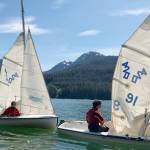 Brendan West, 17, left, and Jack Adams, 15, guide one sailboat while Wesley Torgerson, 16, helps guide another to the dock during a Juneau Youth Sailing course this week. (Therese Pokorney / Juneau Empire)
