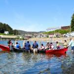 Angoon students prepare to paddle the unity canoe they built with master carver Wayne Price. Crew from the Polynesian voyaging canoe Hōkūle‘a help steady the canoe while their teacher, Chenara Johnson, looks on June 19. (Photo by Claire Stremple/Alaska Beacon)
