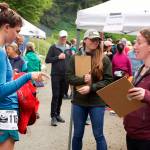 Lauren Tanel, left, shows an emergency space blanket to Sarah Lucas during an equipment check before the Juneau Ridge Race on Sunday at Cope Park. Participants in the race were also required to carry a jacket, long-sleeve shirt, hat, gloves, water and food. (Mark Sabbatini / Juneau Empire)
