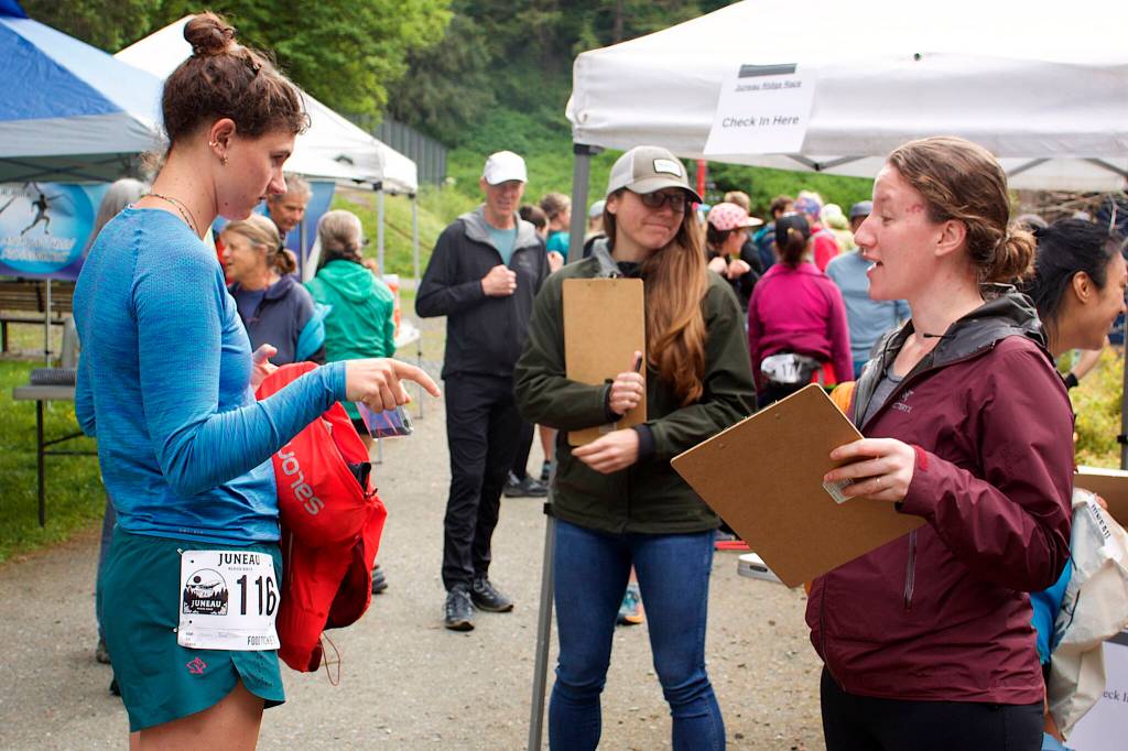 Lauren Tanel, left, shows an emergency space blanket to Sarah Lucas during an equipment check before the Juneau Ridge Race on Sunday at Cope Park. Participants in the race were also required to carry a jacket, long-sleeve shirt, hat, gloves, water and food. (Mark Sabbatini / Juneau Empire)