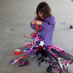 Acacia Forbes, 6, decorates her bike in preparation for July 4 in the Douglas Library parking garage Saturday. (Therese Pokorney / Juneau Empire)