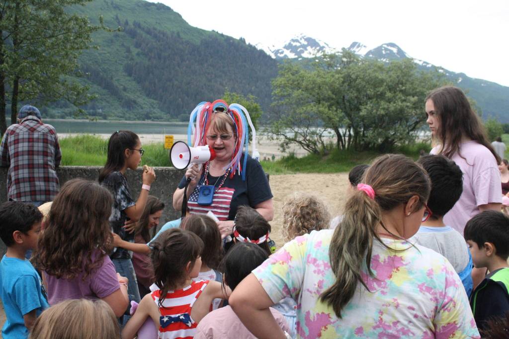 Maggie Swanson, president of the Douglas Fourth of July committee, gives instructions to youths about to participate in a sand dollar search on Sandy Beach during a community picnic Monday evening. (Therese Pokorney / Juneau Empire)