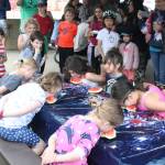 Children participate in a watermelon eating contest Monday evening at a community picnic at Sandy Beach in Douglas. (Therese Pokorney / Juneau Empire)