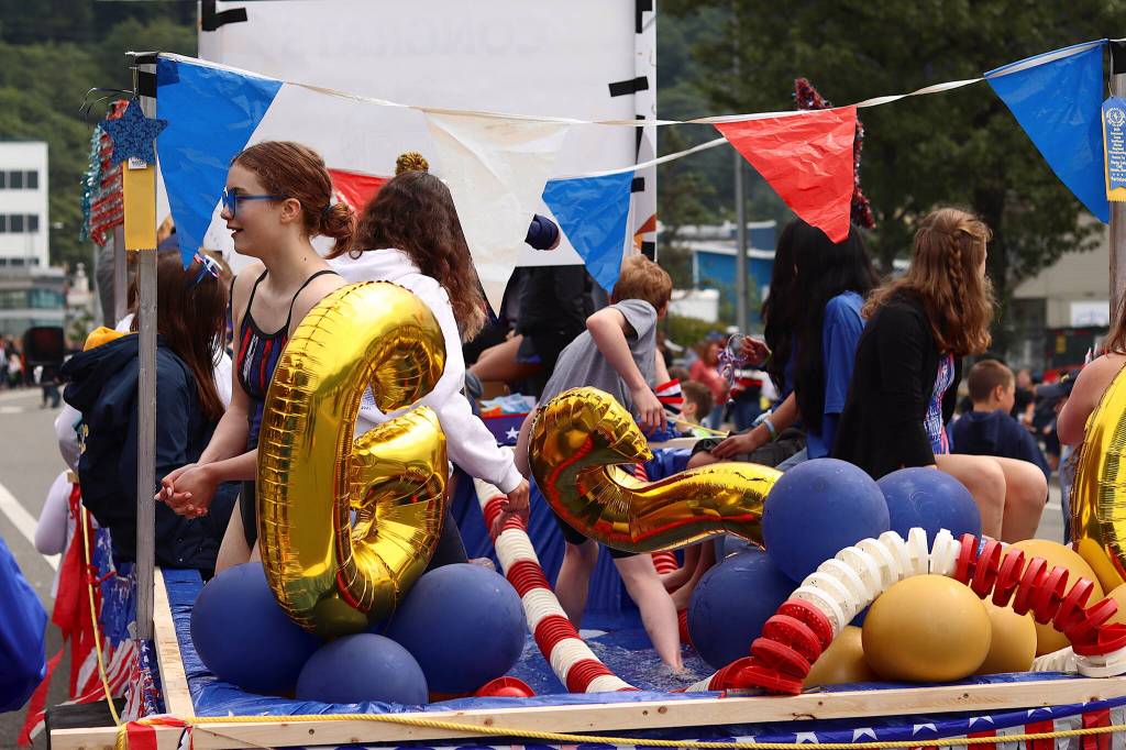 Members of the Glacier Swim Club soak their feet in a wading pool on their float in the Fourth of July parade through downtown Juneau on Tuesday. (Mark Sabbatini / Juneau Empire)