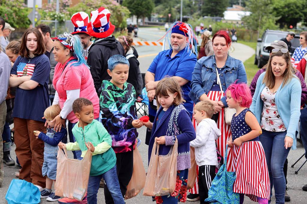 Children compare their collections of candy and other items during the Fourth of July parade in downtown Juneau on Tuesday. (Mark Sabbatini / Juneau Empire)