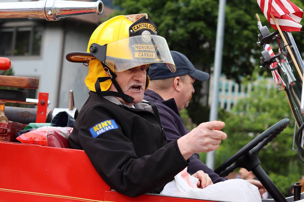 Pete Carran, a grand marshal Juneaus Fourth of July parade, wears the hat he received from Capital City Fire/Rescue when he was named an honorary firefighter in 2014 as he rides in an antique fire truck during the parade. (Mark Sabbatini / Juneau Empire)