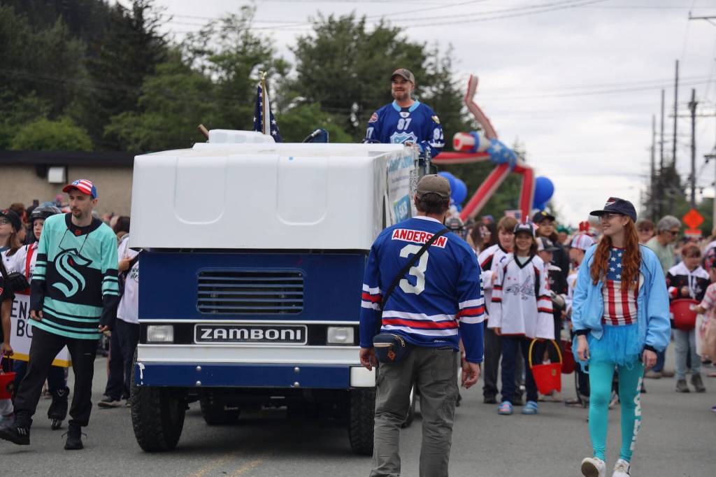 The Juneau Douglas Ice Association team members walk alongside a Zamboni Tuesday afternoon during the annual Fourth of July parade in Douglas. (Clarise Larson / Juneau Empire)
