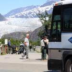 A bus picks up visitors at the Mendenhall Glacier Visitor Center Friday morning. Local tourism companies are being forced to turn away tourists in Juneau seeking to visit the area this summer as commercial tourism limits are being reached rapidly. (Clarise Larson / Juneau Empire)
