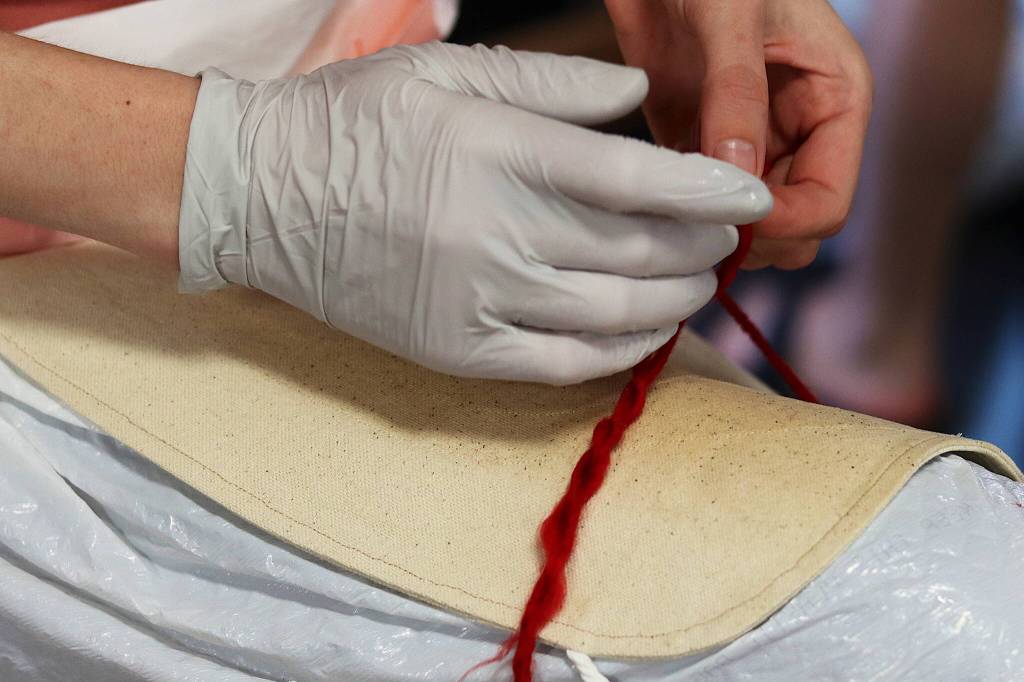 Melina Meyer, a mentor for the Weaving Our Pride project, combines strands of yarn into a stronger thread suitable for weaving into Alaska Native robes during a workshop Friday at the Zach Gordon Youth Center. (Mark Sabbatini / Juneau Empire)