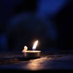 A small candle burns Wednesday night at a pavilion at the Mendenhall Glacier Visitor Center. Dozens of residents gathered to honor Paul Rodriguez Jr. who drowned while kayaking on Mendenhall Lake last week. (Clarise Larson / Juneau Empire)