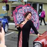 Lily Wooshkindein Da.áat Hope, a Chilkat weaver in Juneau, poses next an antique car for a photo by an audience member during Alaska Fashion Weeks outdoor runway show on Saturday. Hope was among the local designers whose outfits were featured during the show. The antique vehicles were parked along the street to provide ambiance for the outdoor exhibition. (Mark Sabbatini / Juneau Empire)