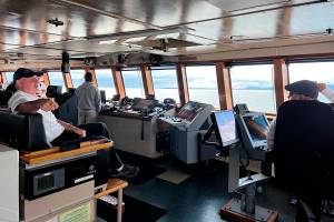 Capt. Dave Turner and Chief Mate Lucas Bevegni on the bridge of Columbia state ferry as Bevegni takes note of a whale spout more than a mile in the distance. (Meredith Jordan / Juneau Empire)