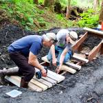 Craig Good (left) and Jim Papoi build a jump along the intermediate-level trail for the new Thunder Mountain Bike Park on Saturday. (Mark Sabbatini / Juneau Empire)