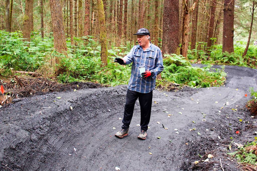 Jack Kreinheder, a board member of both the Juneau Mountain Bike Alliance and Trail Mix, explains the planning process for the turns and other features on the beginners trail at the new Thunder Mountain Bike Park on Saturday. (Mark Sabbatini / Juneau Empire)