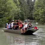 A jet boat belonging to a couple who live in one of the homes where road access was cut off by flooding ferries residents in the flooded area to safety on View Drive on Saturday evening. The couples boat used for hours to shuttle people, pets and possessions across the flooded stretch of street. (Photo by Karie Sims)