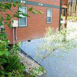 A corner of a condominium complex hangs over the edge of an eroded bank along the Mendenhall River on Sunday morning. Residents of two complexes on the property were forced to evacuate their homes Saturday and were continuing to remove belongings Sunday as doubts were expressed by some about whether the structures can be saved. (Mark Sabbatini / Juneau Empire)
