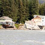A home owned by Amanda Arra, at left, hangs over the edge of an eroded riverbank Sunday after part of the neighboring house fell into the Mendenhall River during record flooding Saturday. (Mark Sabbatini / Juneau Empire)