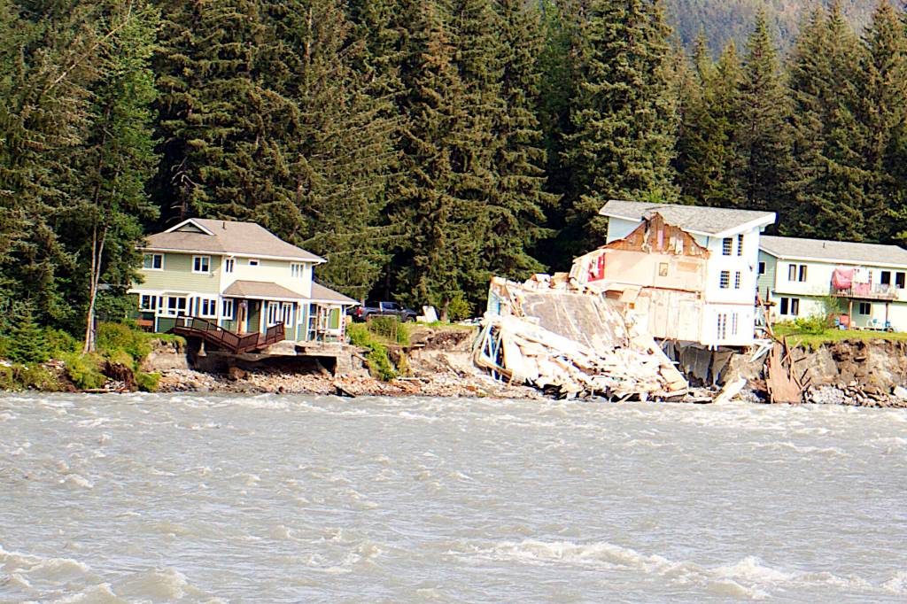 A home owned by Amanda Arra, at left, hangs over the edge of an eroded riverbank Sunday after part of the neighboring house fell into the Mendenhall River during record flooding Saturday. (Mark Sabbatini / Juneau Empire)
