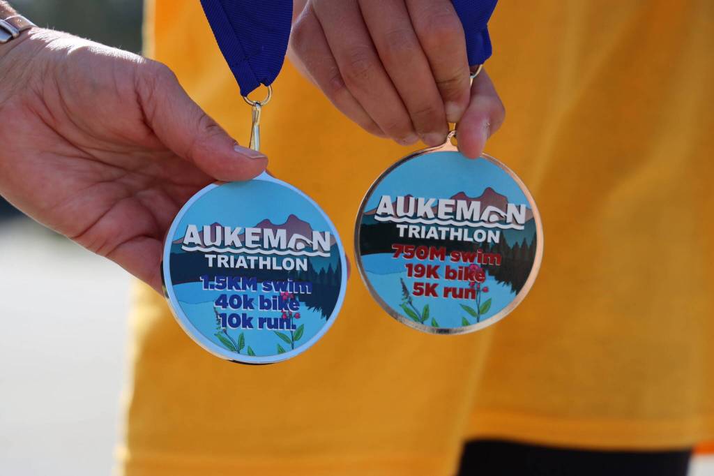 Volunteers hold the two medals handed out to the respective racers of the Olympic and sprint races of the Aukeman Triathlon held at the University of Alaska Southeast campus Sunday morning. (Clarise Larson / Juneau Empire)
