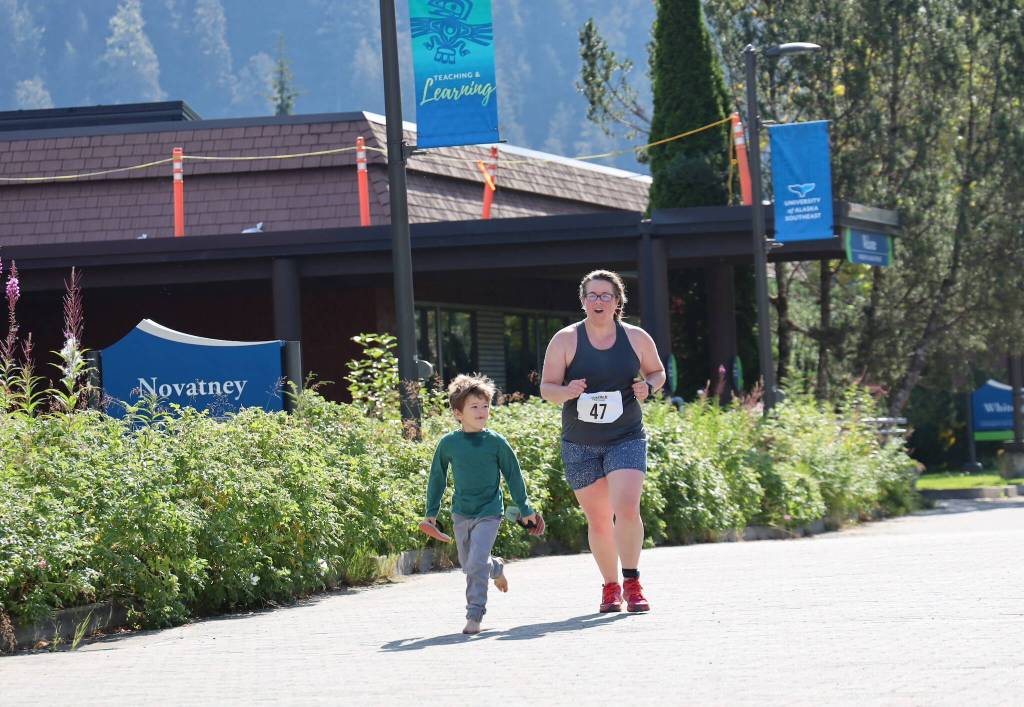 Erin Heard heads to the finish line with the help of her son Parker, 5, as she completes the sprint race of the Aukeman Triathlon at the University of Alaska Southeast campus on Sunday. (Clarise Larson / Juneau Empire)