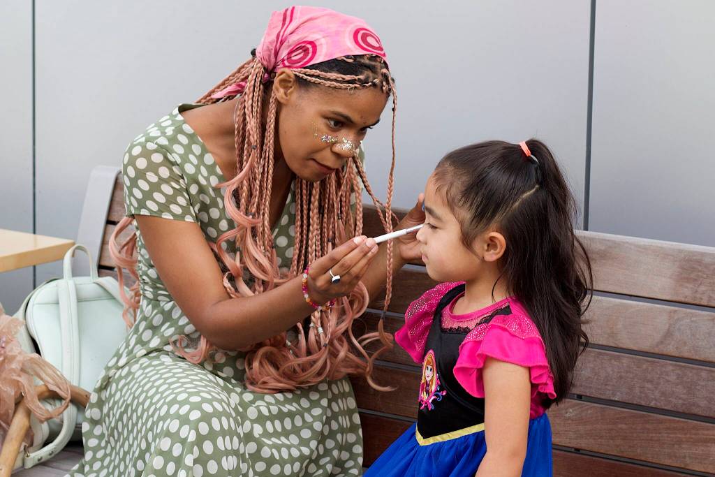 Lacey Davis, a librarian at the Mendenhall Valley Public Library, paints the face of Azalea Lee, 5, at the end of a Drag Storytime on Saturday. (Mark Sabbatini / Juneau Empire)
