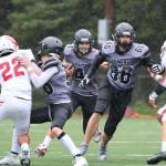 Players protect Jayden Johnson, a junior wide receiver and ​​defensive back, as he runs with the ball during the first quarter of the Juneau Huskies season opener against East Anchorage Saturday afternoon at Adair-Kennedy Memorial Park. (Clarise Larson / Juneau Empire)