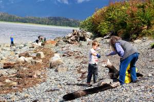 Amos Andreassen, 6, hands a piece of debris to his grandmother, Peggy Tutu, on a beach in North Douglas during a community cleanup Sunday following last weekends record flooding of the Mendenhall River. (Mark Sabbatini / Juneau Empire)