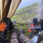 The author, his wife Abby and his friend Danny wait out the weather under a rock and a tarp on opening day of deer season. (Photo by Jeff Lund)