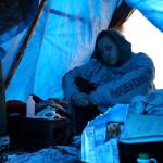 Cherish Ann Blake, 33, a lifelong resident of Juneau, sits under her A-frame staked out between thin trees holding up blue tarps at the Mill Campground on Tuesday afternoon. (Clarise Larson / Juneau Empire)