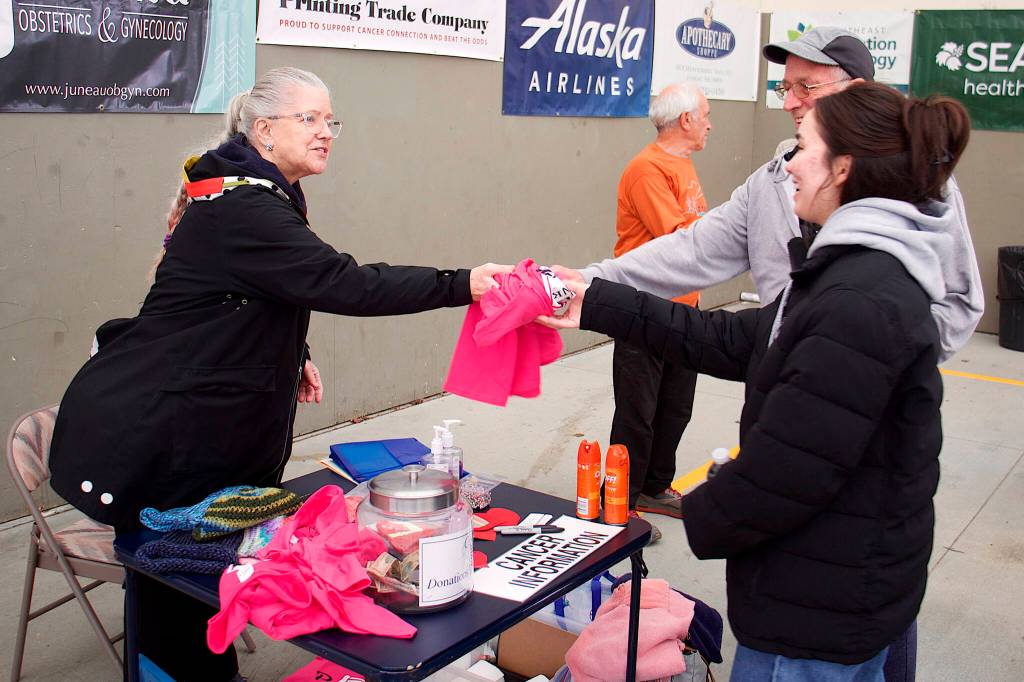 John Eldridge and his daughter, Lisa, 21, get a pink cancer awareness t-shirt from Eileen Hosey, vice president of Cancer Connection, before the start of the 32nd Annual Beat the Odds: A Race Against Cancer event at Kax̱dig̱oowu Héen Elementary School on Saturday morning. The race is a fundraiser for Cancer Connection, which provides services such as travel assistance for people needing treatment outside Juneau. (Mark Sabbatini / Juneau Empire)