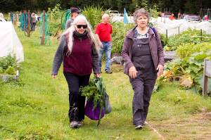 Pauline Plumb and Penny Saddler carry vegetables grown by fellow gardeners during the 29th Annual Juneau Community Garden Harvest Fair on Saturday. (Mark Sabbatini / Juneau Empire)