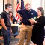 Sam Hatch (left) and Amanda Hatch (right) show pictures of their flood-damaged home to Mike Macans, an individual assistance branch chief for the Alaska Division of Homeland Security and Emergency Management, at a newly opened disaster assistance center at the Mendenhall Valley Public Library on Monday. State and local officials are offering in-person assistance at the center through Wednesday to people affected by record flooding from Suicide Basin earlier this month. (Mark Sabbatini / Juneau Empire)